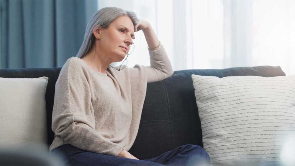 Femme assise seule dans une chambre faiblement éclairée, regard dans le vide, illustrant la solitude émotionnelle vécue dans un couple dont la communication est brisée