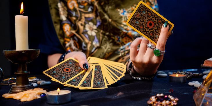 Consultation de voyance amour avec bougies allumées, cartes de tarot et mains jointes sur une table en bois